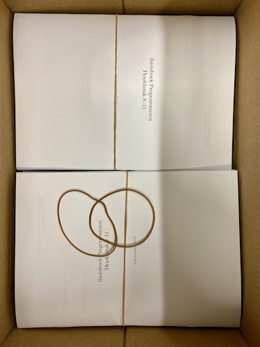 photo of the inside of a box containing a couple of prints of the book, bundled with thin rubber bands